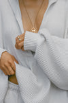 Close up detail front view of model posing in the oversized pearl grey luxe knit Deep V Pullover with a plunging collared neckline and dropped shoulders