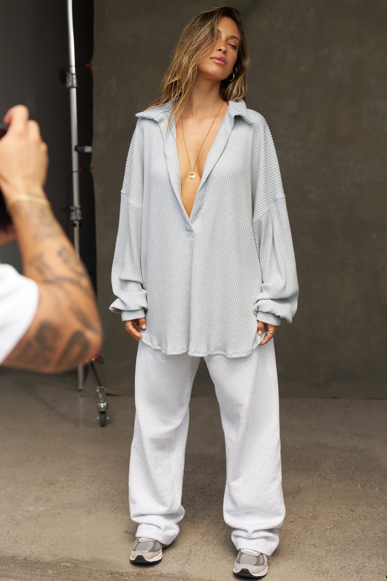 Full body front view of model posing in the oversized pearl grey luxe knit Deep V Pullover with a plunging collared neckline and dropped shoulders