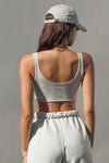 Back view of model posing in the ultra cropped lightweight fog cotton Sporty Crop tank top with a raw hem, scoop back and ribbed accents at neckline and shoulders