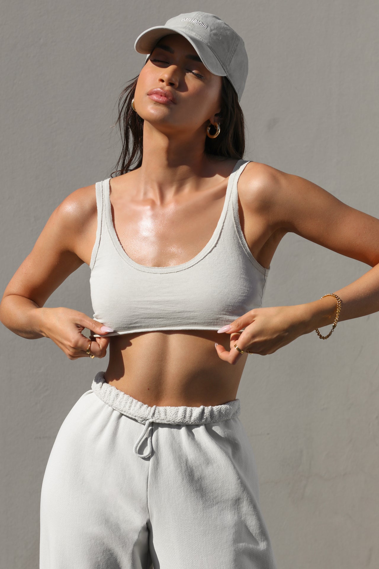Front view of model posing in the ultra cropped lightweight fog cotton Sporty Crop tank top with a raw hem, scoop neckline, and ribbed accents at neckline and shoulders