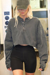 Front view of model posing in the cropped, loose-fitting washed black cotton Vintage Henley Long Sleeve top with dropped shoulders and custom JOAH BROWN buttons