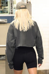 Back view of model posing in the cropped, loose-fitting washed black cotton Vintage Henley Long Sleeve top with dropped shoulders and custom JOAH BROWN buttons