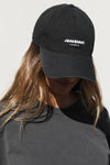 Front view of model wearing the six-panel black with bubble print Official Cap with a curved brim and an embroidered white Joah Brown bubble logo on the front