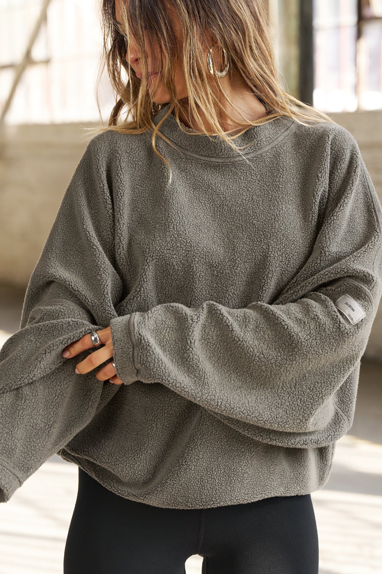 Front view of model posing in the relaxed fit oakmoss sherpa Drop Shoulder Pullover sweatshirt with an exaggerated crew neckline, dropped shoulders and a custom Joah Brown Logo Patch on the left sleeve 