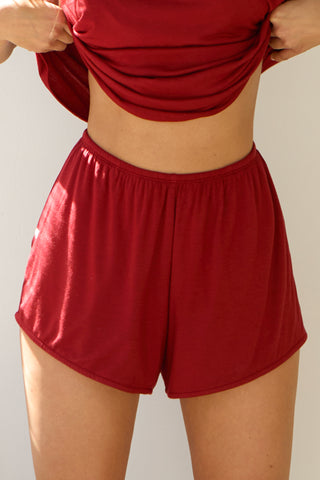 Close up front view of model from the waist down posing in the relaxed-fit cherry modal Easy Short with an elastic waistband, side pockets and subtle pleating for added shape and dimension