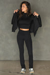 Full body front view of model posing in the full length bootcut sueded onyx Second Skin Bootcut Legging with a wide v-shaped waistband and split detail at the leg opening