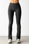 Front view of model from the waist down posing in the full length bootcut sueded onyx Second Skin Bootcut Legging with a wide v-shaped waistband and split detail at the leg opening