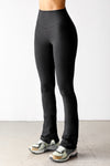 Front view of model from the waist down posing in the full length bootcut sueded onyx Second Skin Bootcut Legging with a wide v-shaped waistband and split detail at the leg opening