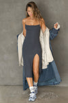 Full body front view of model posing in the stretchy form fitting vintage navy rib Strappy Slit Dress with a high front slit and thin corded straps that hits at mid-calf