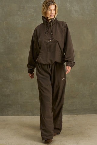 Full body front view of model posing in the relaxed fit espresso nylon 3/4 Zip Windbreaker jacket with a structured collar and 3/4 zip neckline