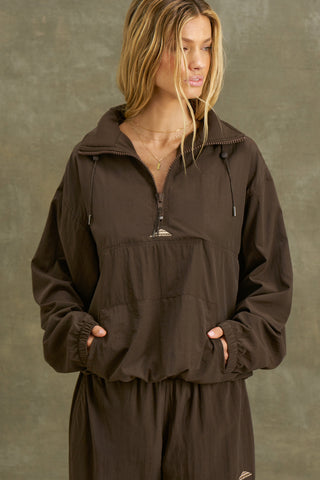 Front view of model posing in the relaxed fit espresso nylon 3/4 Zip Windbreaker jacket with a structured collar and 3/4 zip neckline