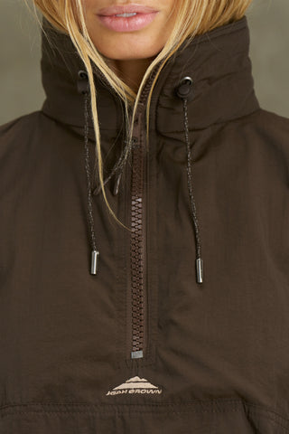 Close up detail front view of model posing in the relaxed fit espresso nylon 3/4 Zip Windbreaker jacket with a structured collar and 3/4 zip neckline