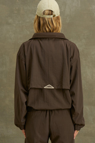Back view of model posing in the relaxed fit espresso nylon 3/4 Zip Windbreaker jacket with a structured collar and 3/4 zip neckline