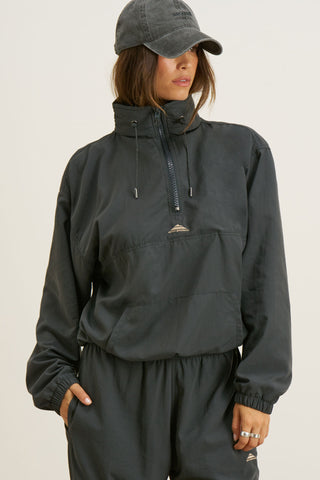 Front view of model posing in the relaxed fit jet nylon 3/4 Zip Windbreaker jacket with a structured collar and 3/4 zip neckline