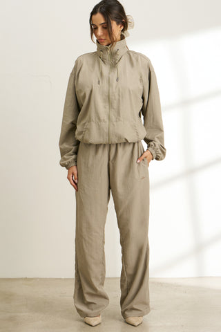 Full body front view of model posing in the relaxed fit desert sage nylon Classic Track Pant with a straight-leg silhouette, adjustable drawstring elastic waistband and side pockets 