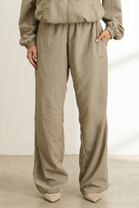 Front  view of model from the waist down posing in the relaxed fit desert sage nylon Classic Track Pant with a straight-leg silhouette, adjustable drawstring elastic waistband and side pockets 