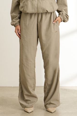 Front  view of model from the waist down posing in the relaxed fit desert sage nylon Classic Track Pant with a straight-leg silhouette, adjustable drawstring elastic waistband and side pockets 