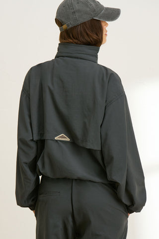 Back view of model posing in the relaxed fit jet nylon 3/4 Zip Windbreaker jacket with a structured collar and 3/4 zip neckline