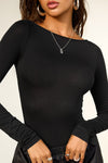 Close up front view of model posing in the fitted, light weight black modal Boatneck Long Sleeve with a boat neckline