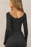 Back view of model posing in the fitted, lightweight black modal Boatneck Long Sleeve with boat neckline and scoop back