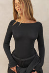 Front view of model posing in the fitted, lightweight black modal Boatneck Long Sleeve with a boat neckline