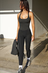Full body front view of model posing in the vintage black flexrib Classic Racerback Tank with a scoop neckine and racerback silhouette. 