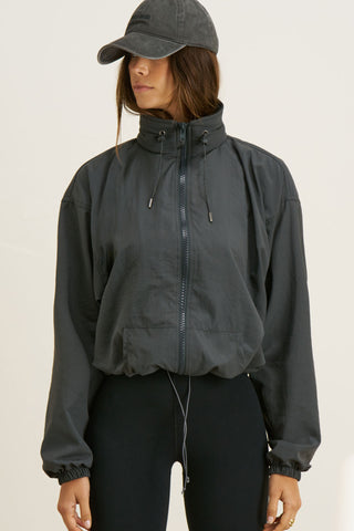 Front view of model posing in the relaxed-fit jet nylon Classic Windbreaker Jacket with a padded collared neck for structure & adjustable corded details at the sweep for cinching