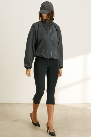 Full body front view of model posing in the relaxed-fit jet nylon Classic Windbreaker Jacket with a padded collared neck for structure & adjustable corded details at the sweep for cinching