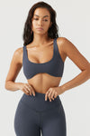Front view of model posing in the stretchy and sculpting sueded navy contour bra with a deep scoop neckline and curved hem
