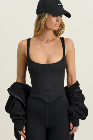 Front view of model posing in the fitted sueded onyx Contour Corset Tank with contour seaming, curved front hem and adjustable straps.