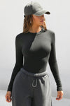 Front view of model posing outside  in the fitted and stretchy vintage black rib Crewneck Long Sleeve with a banded crew neckline