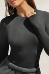 Close up detail front view of model posing in the fitted and stretchy vintage black rib Crewneck Long Sleeve with a banded crew neckline