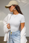 Front view of model posing in the form fitting pearl grey rib Crewneck Tee with a banded crew neckline and banding at the sleeves