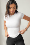 Front view of model posing in the form fitting white rib Crewneck Tee with a banded crew neckline and banding at the sleeves