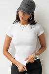 Front view of model posing in the form fitting white rib Crewneck Tee with a banded crew neckline and banding at the sleeves