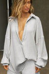 Front view of model posing in the oversized pearl grey luxe knit Deep V Pullover with a plunging collared neckline and dropped shoulders