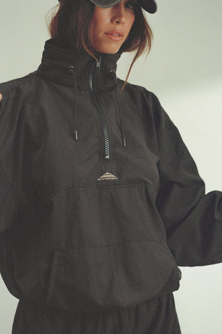 Front view of model posing in the relaxed fit jet nylon 3/4 Zip Windbreaker jacket with a structured collar and 3/4 zip neckline