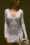 Front view of model posing in the soft and fitted pearl grey luxe knit Asymmetrical Button Mini Dress with long sleeves,  a v-neckline and asymmetrical button-front details. 
