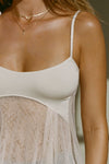 Close up detail front view of model posing in the flowy and sheer black polka dot lace Babydoll Tank with a scoop-neck tank with adjustable spaghetti straps and an open back design.