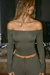 Front view of model posing in the fitted, slightly cropped spruce modal Bare Shoulder Long Sleeve top with a straight, off-the-shoulder neckline