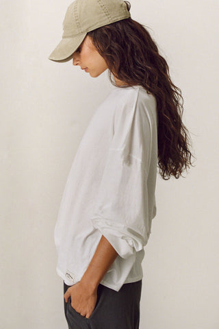 Side view of model posing in the relaxed fit, lightweight optic white classic cotton Boxy Crew Long Sleeve top with a crew neckline, dropped shoulders and oversized silhouette