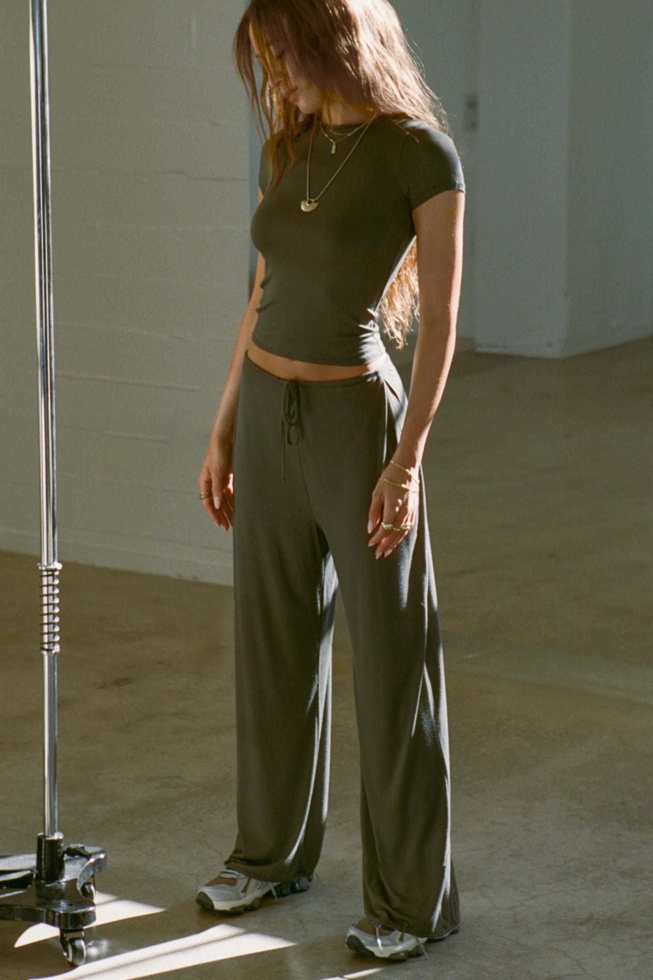 Full body front view of model posing in the relaxed fit spruce modal Relaxed Straight Leg Pant with a wide leg, elastic waistband, adjustable drawstring tie and subtle pleating at the sides.