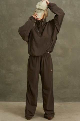 Full body front view of model posing in the relaxed fit espresso nylon Classic Track Pant with a straight-leg silhouette, adjustable drawstring elastic waistband and side pockets 