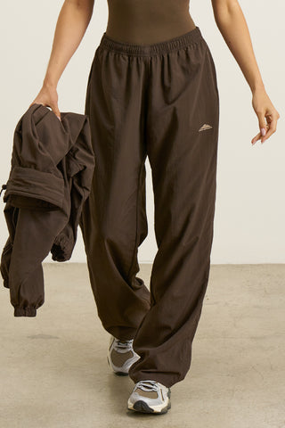 Front view of model from the waist down posing in the relaxed fit espresso nylon Classic Track Pant with a straight-leg silhouette, adjustable drawstring elastic waistband and side pockets 