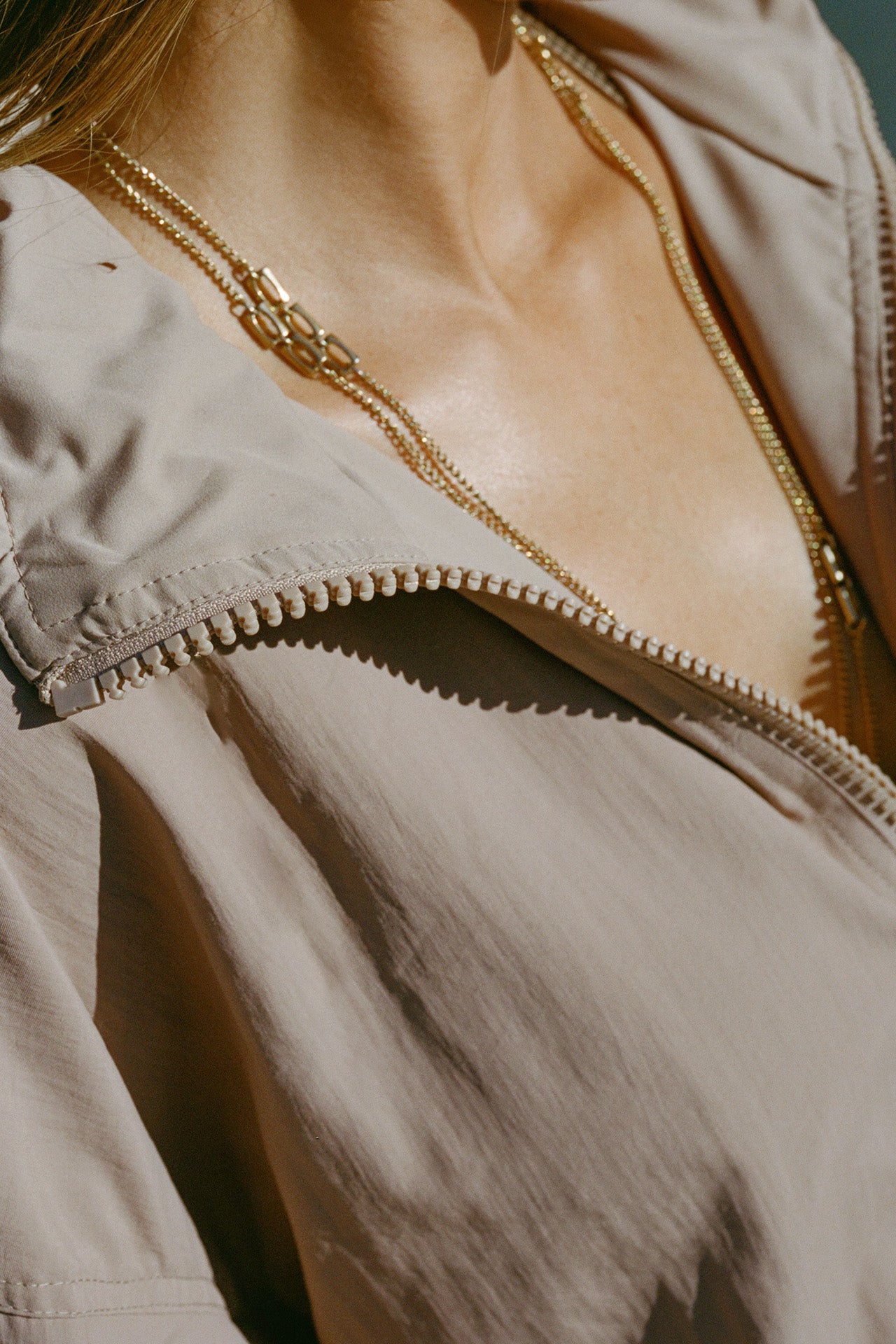 Close up detail front view of model posing in the relaxed-fit fawn Classic Windbreaker Jacket with a padded collared neck for structure & adjustable corded details at the sweep for cinching