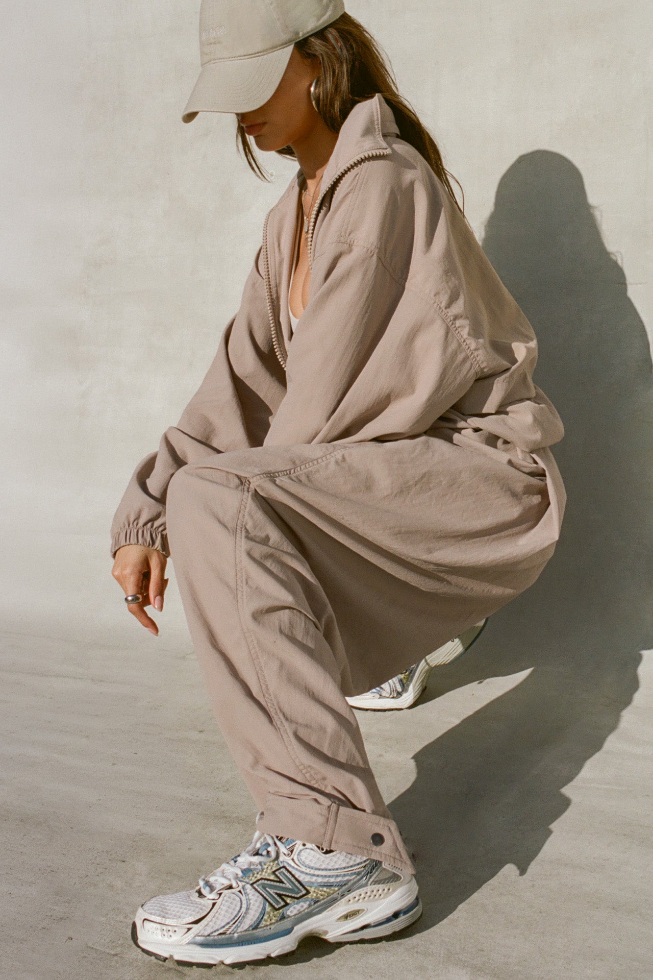 Side view of model posing in the relaxed-fit fawn Classic Windbreaker Jacket with a padded collared neck for structure & adjustable corded details at the sweep for cinching