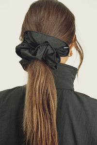 Back view of model posing in the oversized jet Nylon Scrunchie with a voluminous silhouette.