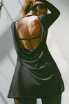 Close up back view model posing in the relaxed fit black modal Cowl Back Long Sleeve Mini Dress \with a crew neckline, A-line silhouette, adjustable straps at the center back and neck and an open back with a draped cowl detail.