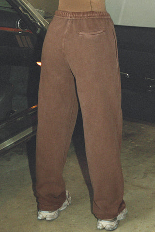 Back view of model from the waist down posing in the relaxed fit cedar french terry Oversized Straight Leg Jogger with an elastic waistband, hidden drawstring, pocket details. and adjustable cinching at the ankle cuffs