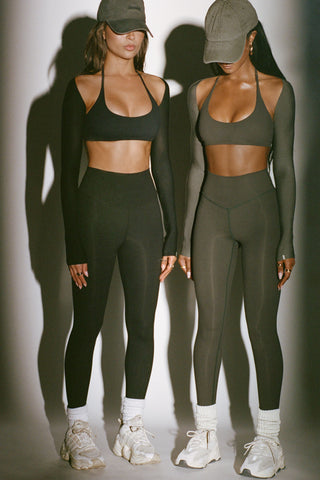 Two models posing in the ultra-cropped and lightweight black and spruce modal Shrug bolero cardigans fitted long sleeves